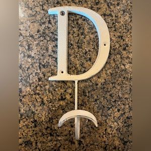 Cream/off white metal hanging letter “D” to hang towels, keys, or clothes on.